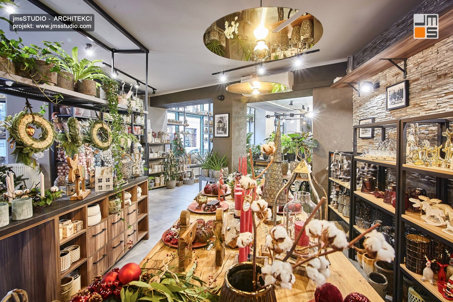 duży drewniany stół i eleganckie stalowe regały oraz złote lampy w projekt wnętrz kwiaciarni w Krakowie