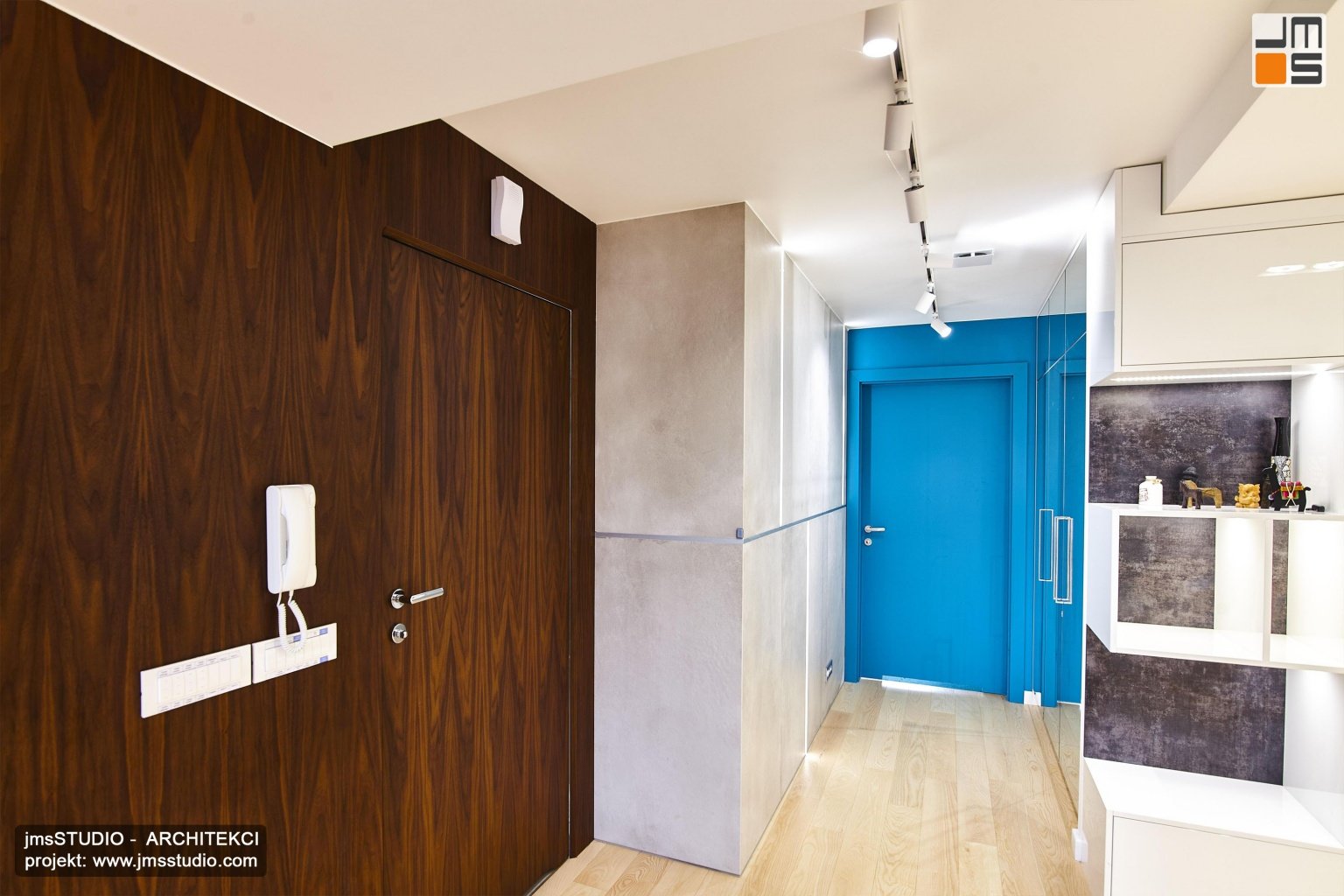 Pomysł na projekt wnętrz holu w apartamencie to trzy kolorowe płaszczyzny pomysł na drewnianą ścianę z ukrytymi drzwiami oraz turkusowe lakierowane drzwi i beton architektoniczny