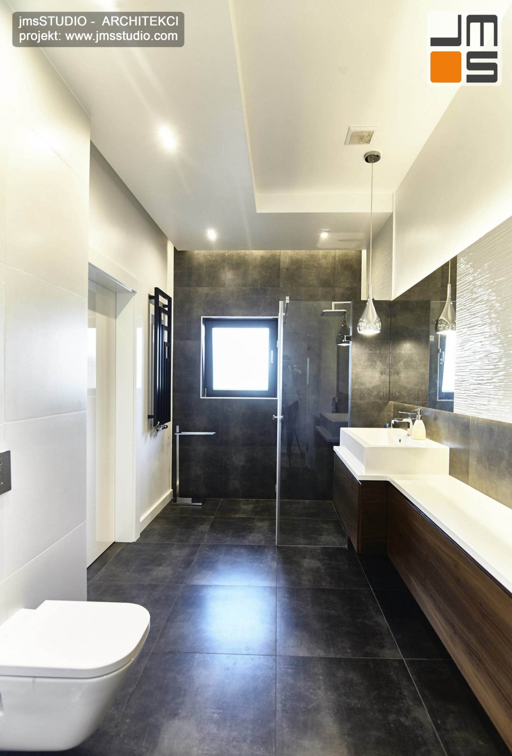 2018 06 w małej  łazience o dziwnym kształcie projekt wnętrz wprowadził sufit podwieszany z ciekawym oświetleniem oraz meble z drewna orzech i ciemne płytki